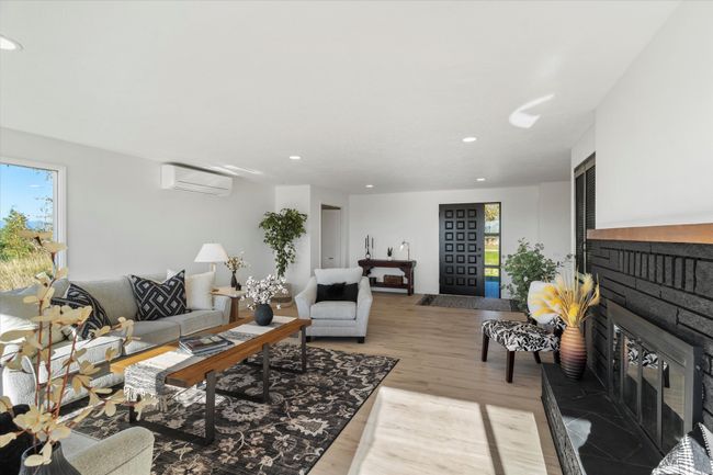 Living room with light hardwood / wood-style flooring, a fireplace, and a wall unit AC | Image 12