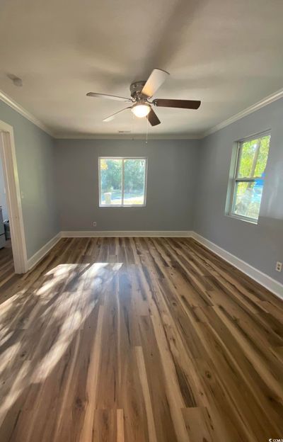 Spare room featuring crown molding, a wealth of natural light, dark hardwood / wood-style floors, and ceiling fan | Image 3