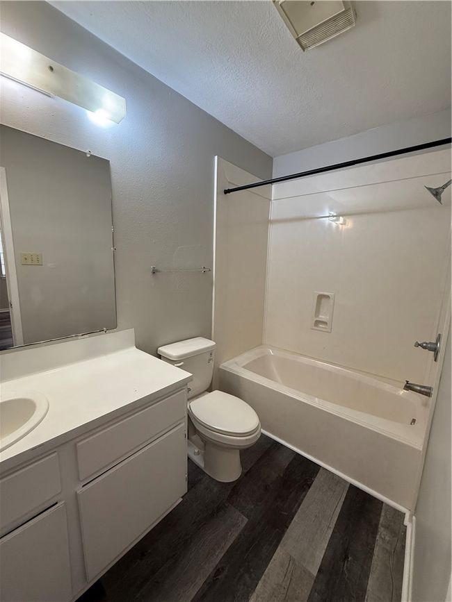 Bathroom featuring dark wood finished floors, washtub / shower combination, a textured ceiling, and vanity | Image 14