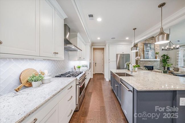 Open kitchen with an upgraded 36' range and 36" stainless steel hood and blower | Image 11