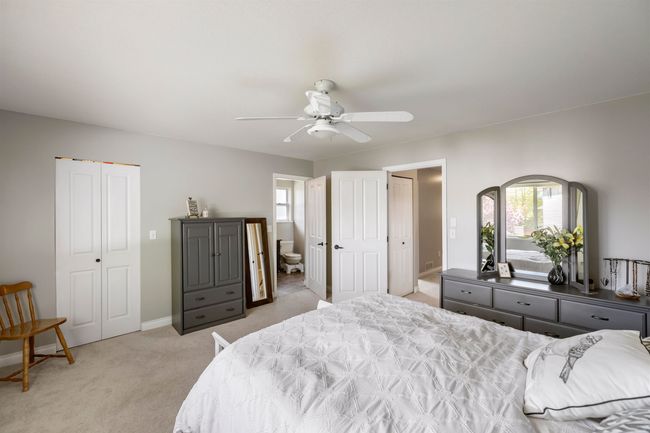 Bedroom with baseboards, light colored carpet, multiple windows, and ensuite bathroom | Image 16