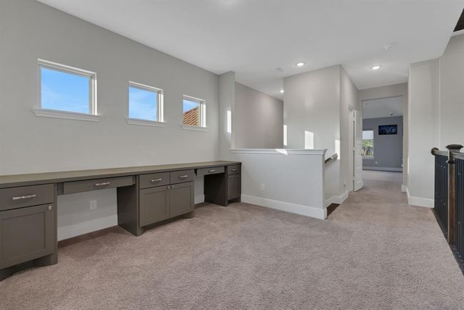 Built-in desks and cabinets, ideal for a home office or study area. Natural light streams through three small windows, enhancing the open and airy feel. | Image 40