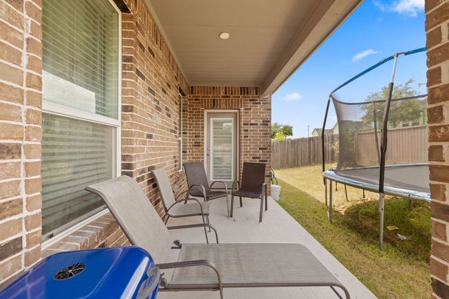 Fenced backyard featuring a trampoline and a patio | Image 30