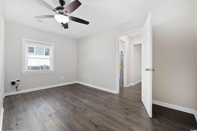 Unfurnished room featuring dark wood-style floors, a ceiling fan, baseboards, and water heater | Image 23