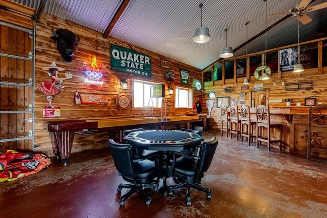 Recreation room featuring high vaulted ceiling, wooden walls, and finished concrete flooring | Image 4
