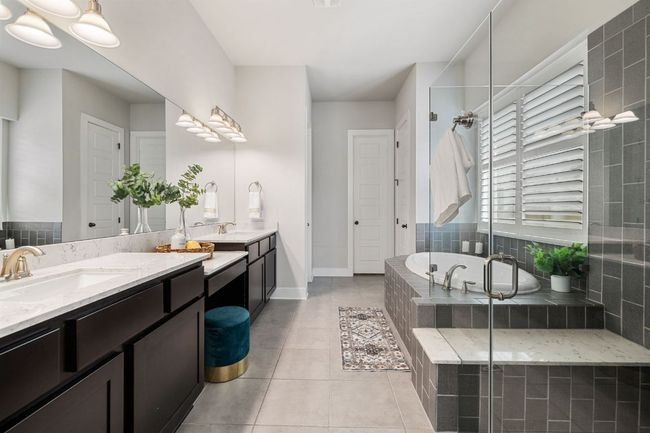 Primary bathroom has a glassed in shower, large oval soaking tub, and a double vanity. | Image 22