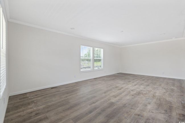 Spare room featuring ornamental molding and wood finished floors | Image 7