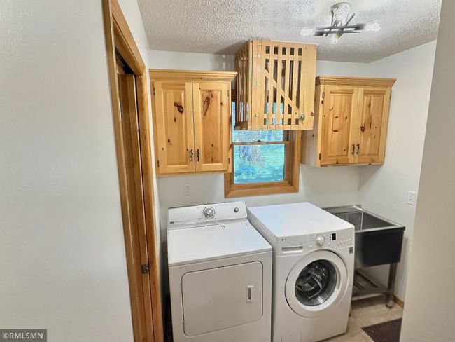 Just off the kitchen is a laundry room complete with a sink, to the right is the garage, to the left a half bathroom. | Image 14