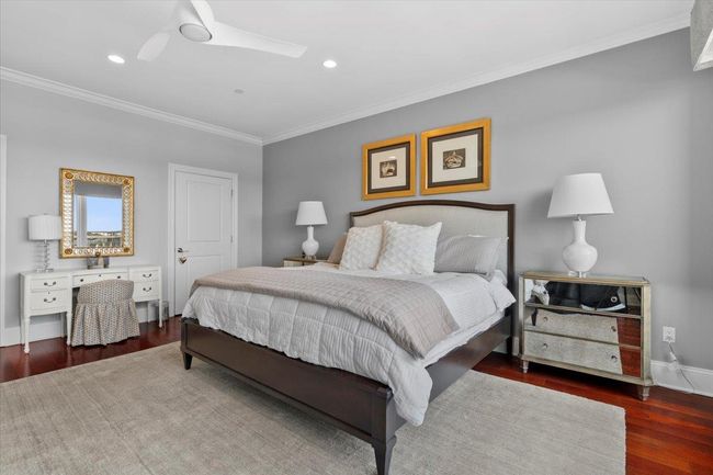 Bedroom with visible vents, crown molding, wood finished floors, baseboards, and a water view | Image 11