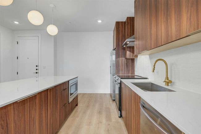 Kitchen with modern cabinets, wall chimney range hood, stainless steel appliances, brown cabinetry, and recessed lighting | Image 5