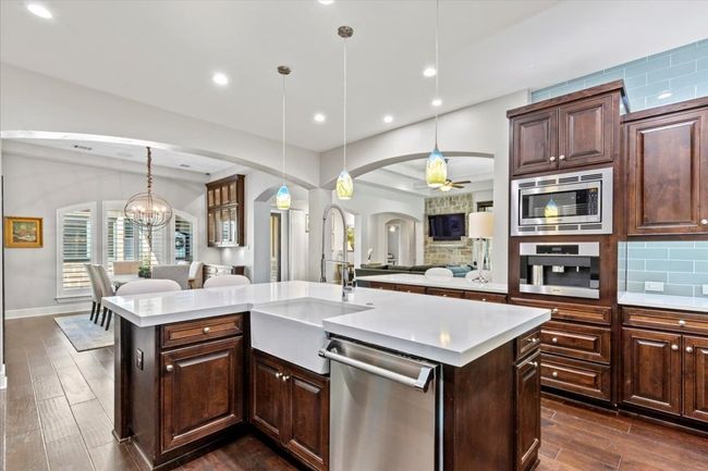 Kitchen featuring light countertops, a sink, arched walkways, appliances with stainless steel finishes, and open floor plan | Image 14