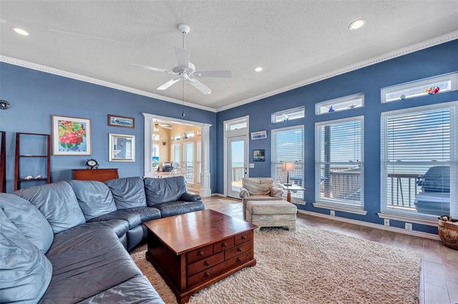 Rows of bay-facing windows fill this space with sunshine and fresh coastal vibes, while wood-look tile plank flooring adds warmth and style. Whether you’re lounging on the couch or heading out to the deck, the bay is always in view. | Image 6
