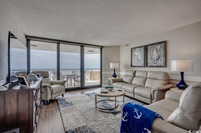 Living room with wood-type flooring, a textured ceiling, and expansive windows | Image 4