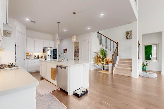 Kitchen featuring light countertops, visible vents, stainless steel appliances, light wood finished floors, and a sink | Image 12