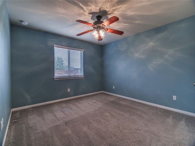 Unfurnished room with carpet flooring, ceiling fan, baseboards, and a smoke detector | Image 11