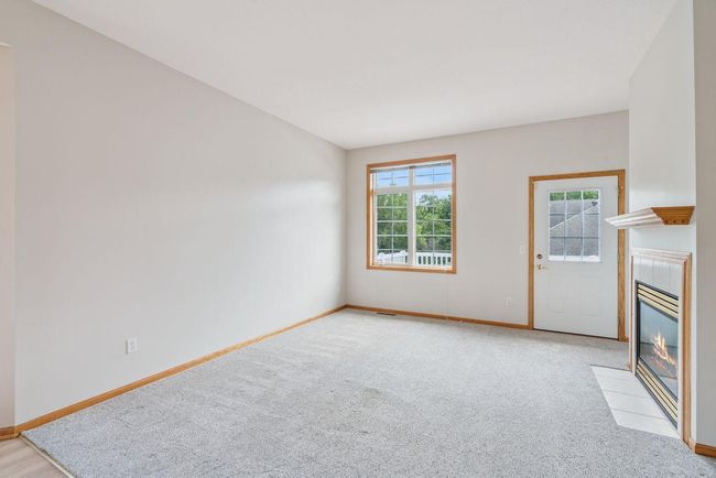 Main level living room with newer carpet, cozy natural gas fireplace, door leading out to large deck (28x10) | Image 13