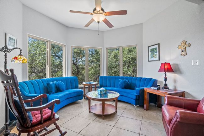 Living area with light tile patterned floors, plenty of natural light, and a ceiling fan | Image 6