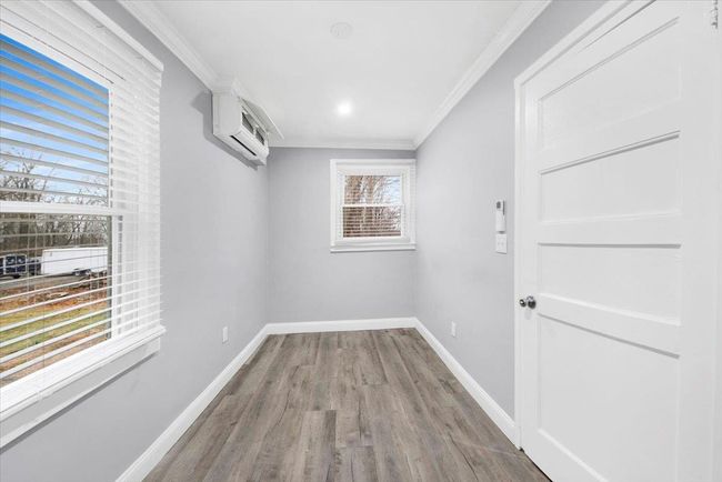 Empty room featuring crown molding, wood finished floors, baseboards, and a wall unit AC | Image 12