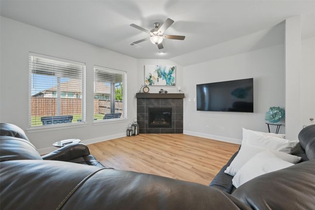 Living room featuring baseboards, ceiling fan, wood finished floors, and a tile fireplace | Image 8