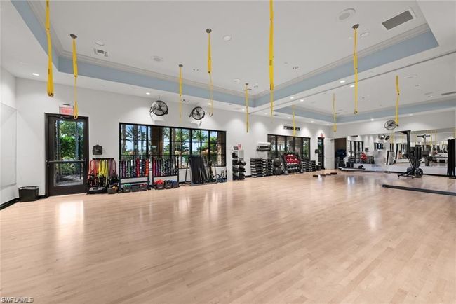 Gym with crown molding, visible vents, wood finished floors, and a raised ceiling | Image 37