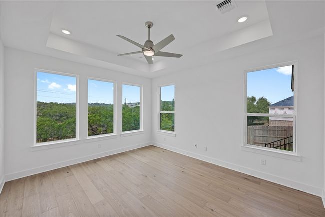 Empty room featuring a tray ceiling, baseboards, ceiling fan, light wood finished floors, and recessed lighting | Image 14
