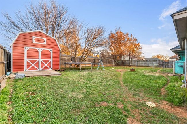 View of yard with a storage unit and a trampoline | Image 21