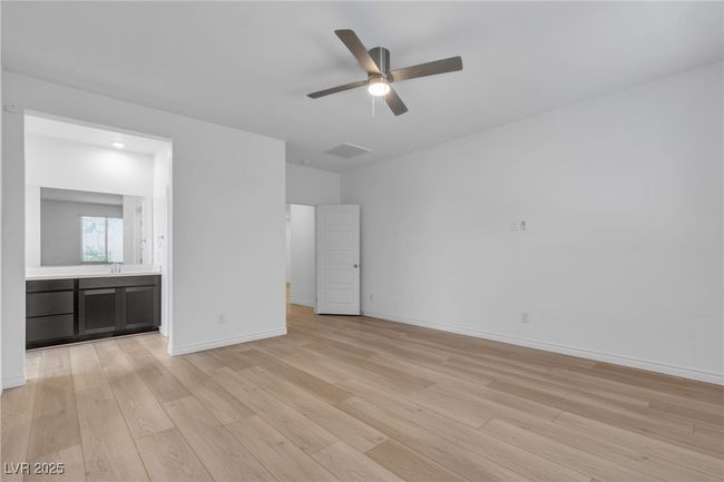 Unfurnished bedroom with light wood finished floors, baseboards, ensuite bath, and a ceiling fan | Image 24