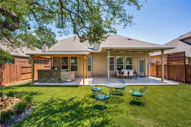 Rear view of property featuring a fenced backyard, a patio, a chimney, a ceiling fan, and roof with shingles | Image 26