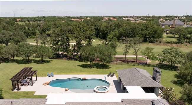 View of pool featuring a yard, a pool with connected hot tub, a patio area, and view of wooded area | Image 25
