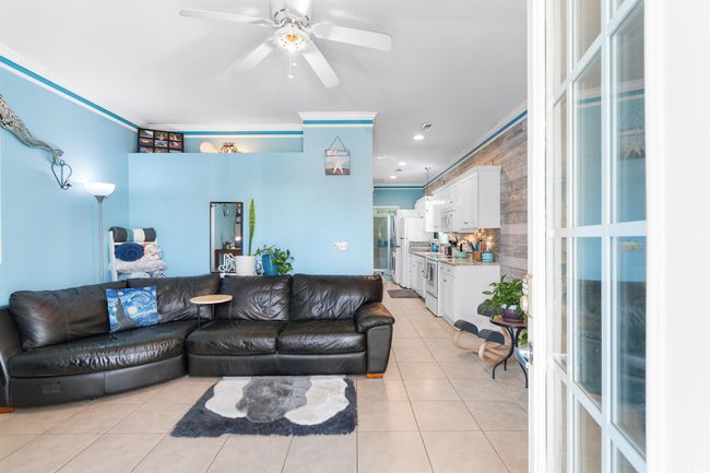 Living area with light tile patterned floors, a ceiling fan, crown molding, and recessed lighting | Image 7