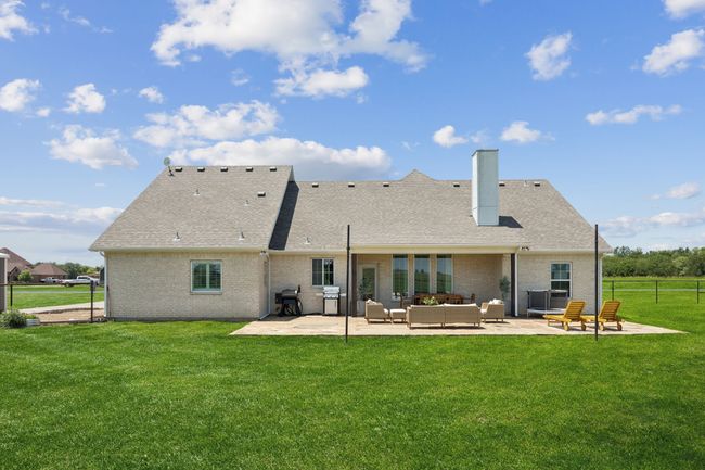 Rear view of property featuring outdoor lounge area, a patio, brick siding, a chimney, and roof with shingles | Image 20