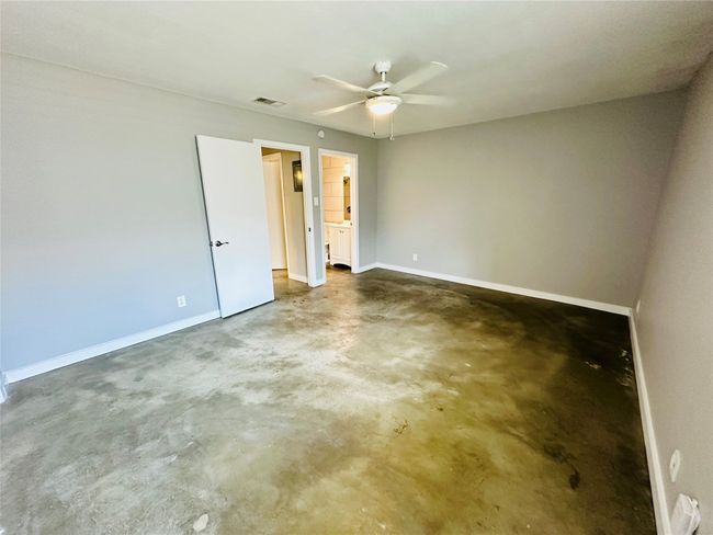 Unfurnished bedroom featuring concrete floors, ensuite bath, and a ceiling fan | Image 13