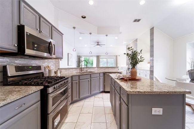 Kitchen featuring appliances with stainless steel finishes, gray cabinetry, recessed lighting, ceiling fan, and tasteful backsplash | Image 9