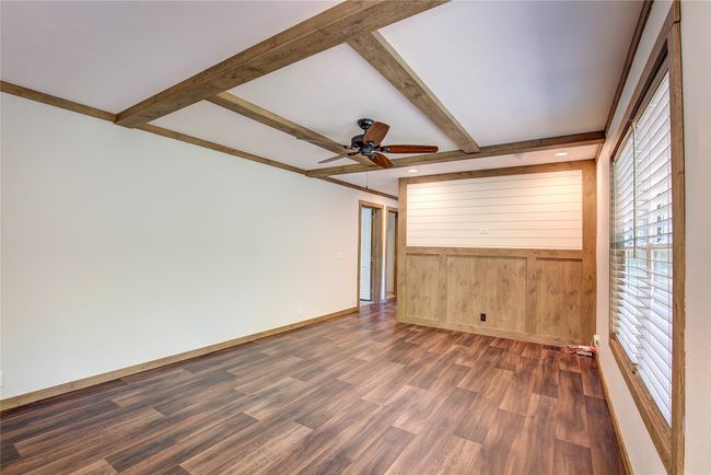 Empty room with dark wood-style floors, beam ceiling, and a ceiling fan | Image 18