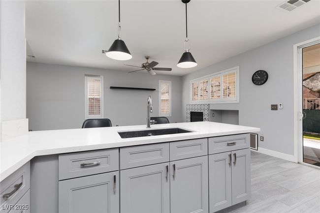 Kitchen with a sink, visible vents, pendant lighting, ceiling fan, and light countertops | Image 11