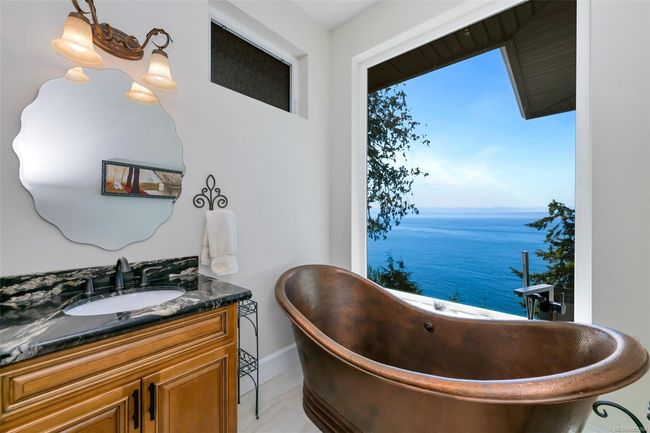 Full bath with double vanity, a freestanding tub, a water view, and healthy amount of natural light | Image 12