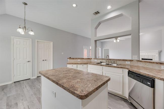 Kitchen with dishwasher, a sink, vaulted ceiling, a ceiling fan, and a center island | Image 8