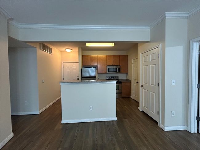 Kitchen with visible vents, brown cabinetry, dark wood-style floors, appliances with stainless steel finishes, and crown molding | Image 7