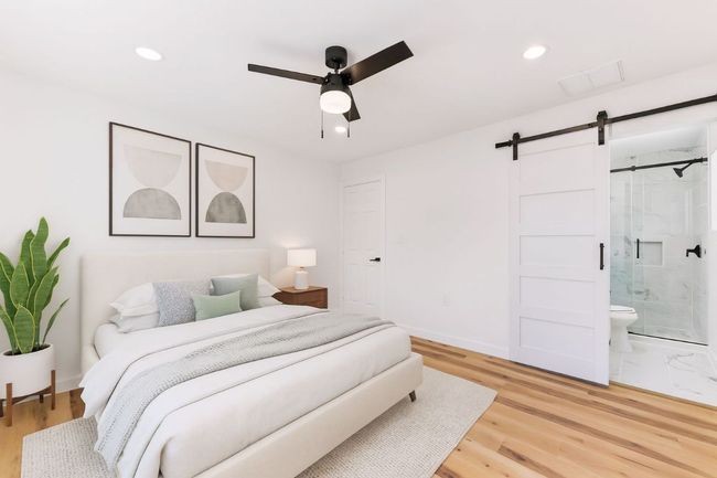 Bedroom with a barn door, light wood-style flooring, recessed lighting, ceiling fan, and ensuite bath | Image 20
