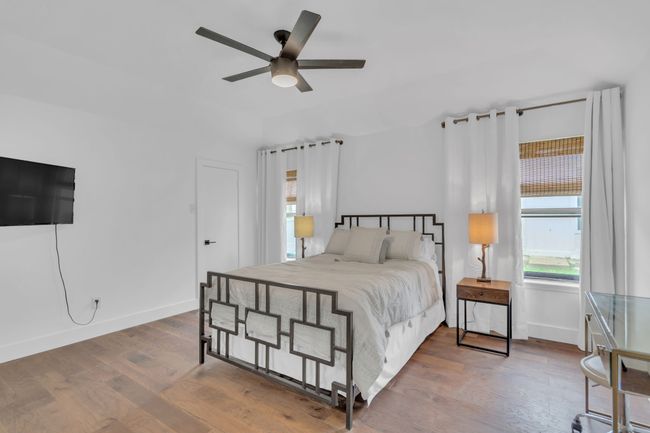 Bedroom featuring a ceiling fan, baseboards, multiple windows, and wood finished floors | Image 24
