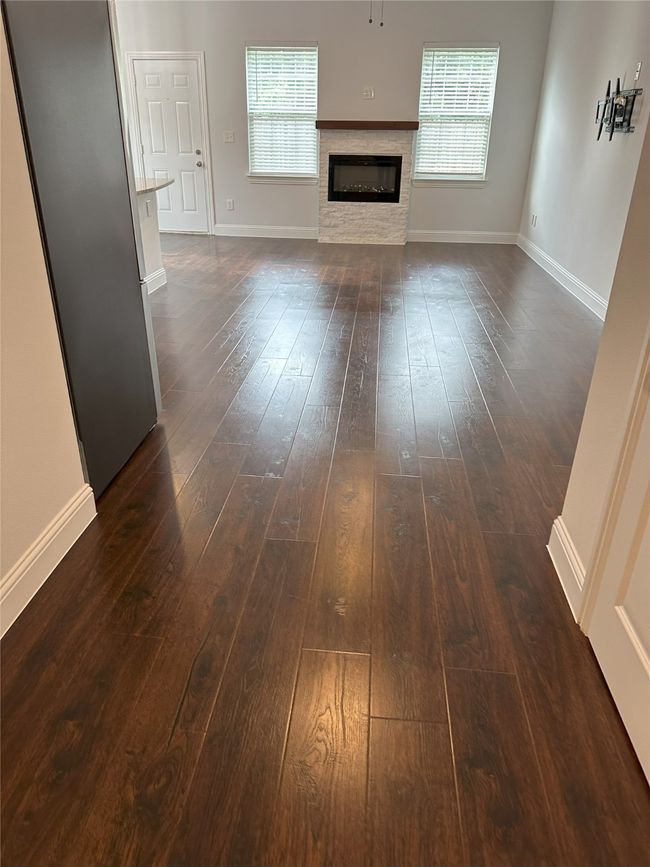 Unfurnished living room featuring dark wood-type flooring and a glass covered fireplace | Image 5