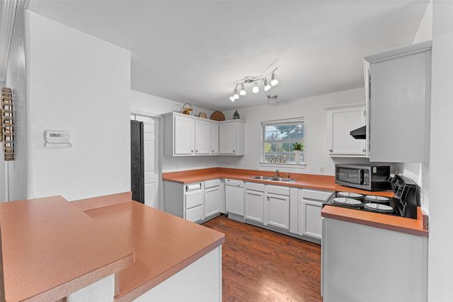 Kitchen featuring stainless steel microwave, dark wood-style floors, and white cabinetry | Image 10