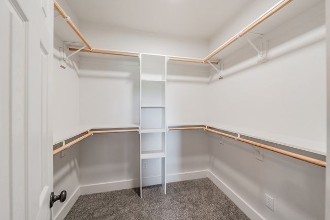 Walk in closet featuring dark colored carpet | Image 34