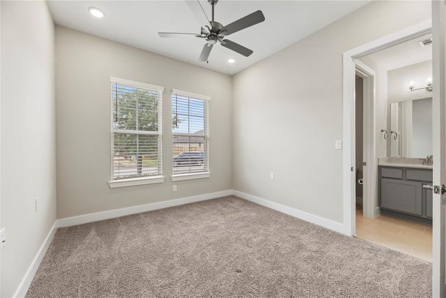 Your family and guests will rest comfortably in this spacious guest suite, featuring plush carpet, a ceiling fan, a large walk-in closet, and ensuite access to a full bathroom for added privacy and convenience. | Image 23