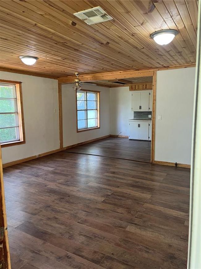 Unfurnished living room with wood ceiling, baseboards, and dark wood-style flooring | Image 10