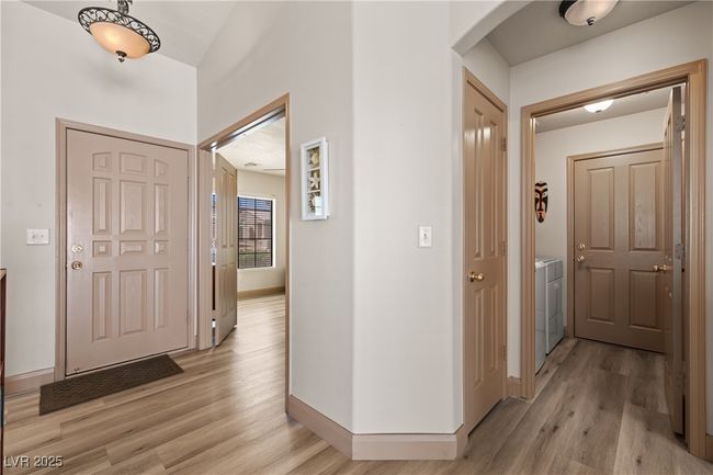 Corridor with light wood-style floors, arched walkways, and washer and dryer | Image 6