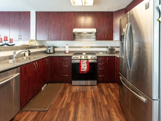 Kitchen featuring a sink, stainless steel appliances, reddish brown cabinets, and under cabinet range hood | Image 11