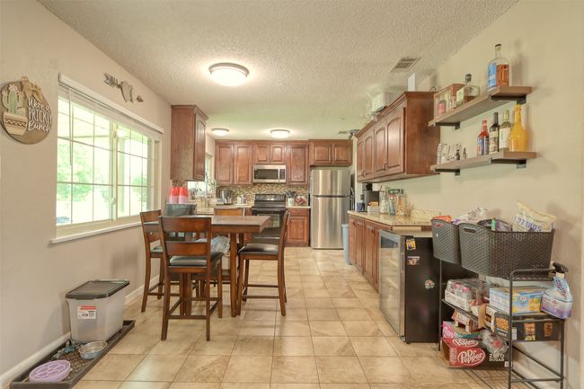 Kitchen with stainless steel appliances, light countertops, a textured ceiling, decorative backsplash, and open shelves | Image 14