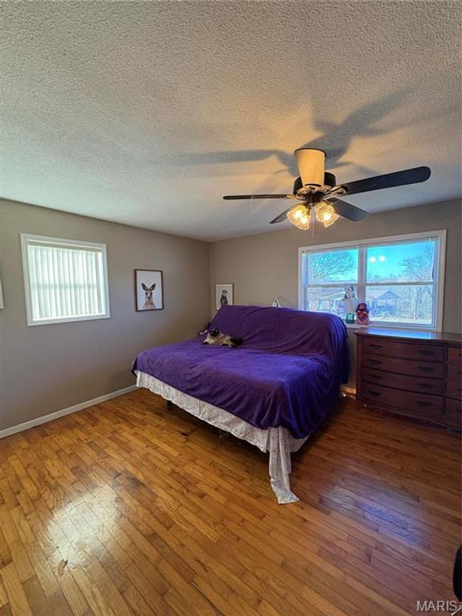 Bedroom featuring a textured ceiling, ceiling fan, hardwood / wood-style flooring, and baseboards | Image 17
