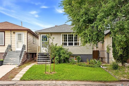 Front exterior featuring a stucco finish, a gray asphalt shingle roof, and multiple windows | Card Image